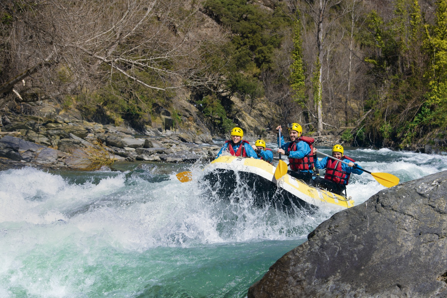 Group of people going over rapids whilst white water rafting