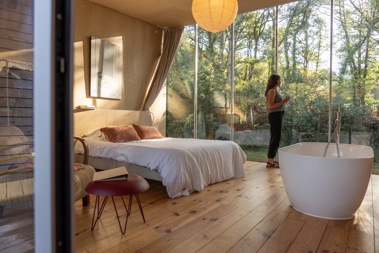 Woman standing in hotel room looking out of window - Brittany, France