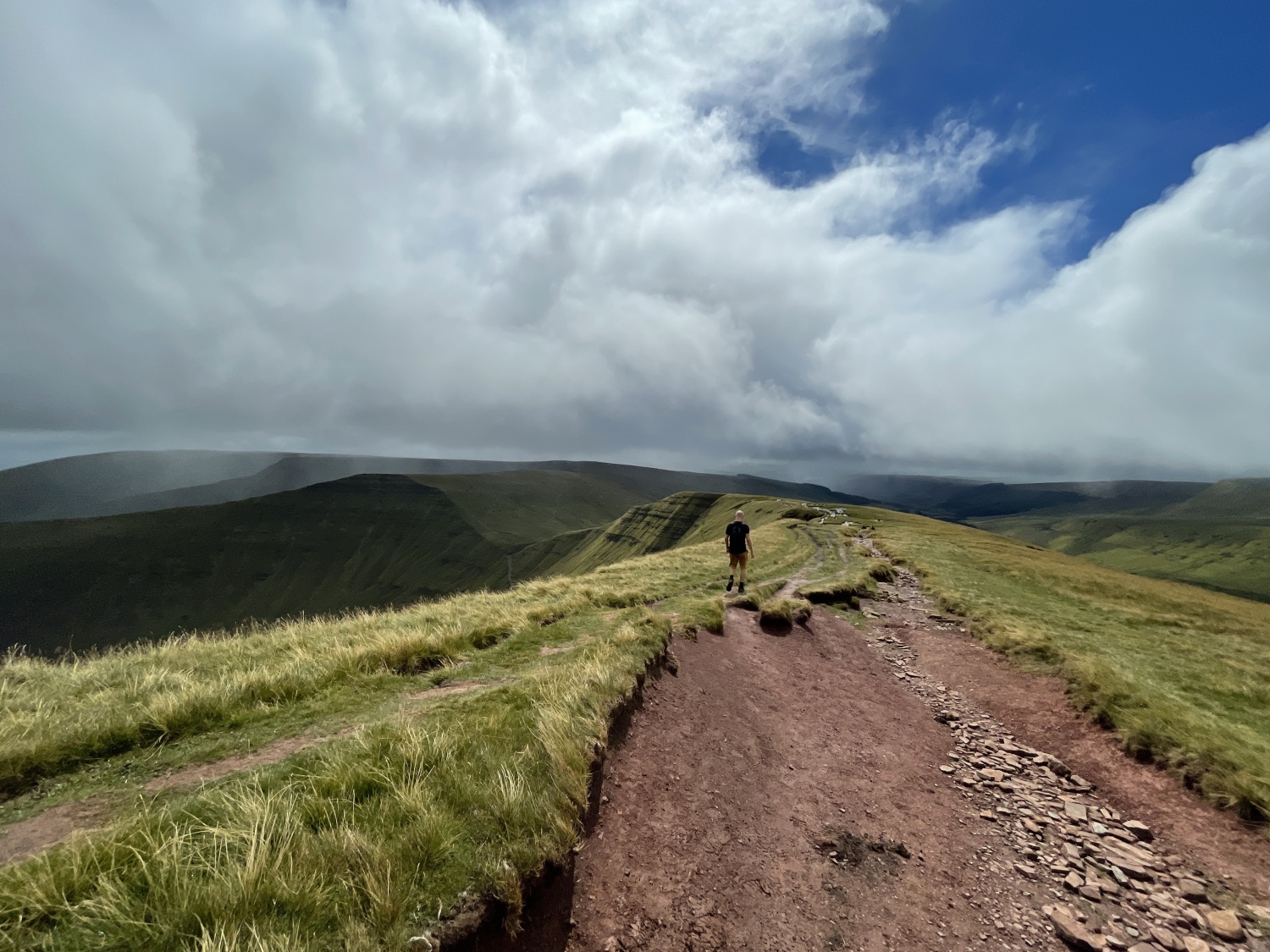 Man walking along Pen y Fan footpath with misty mountains in background - Climbing Pen y Fan